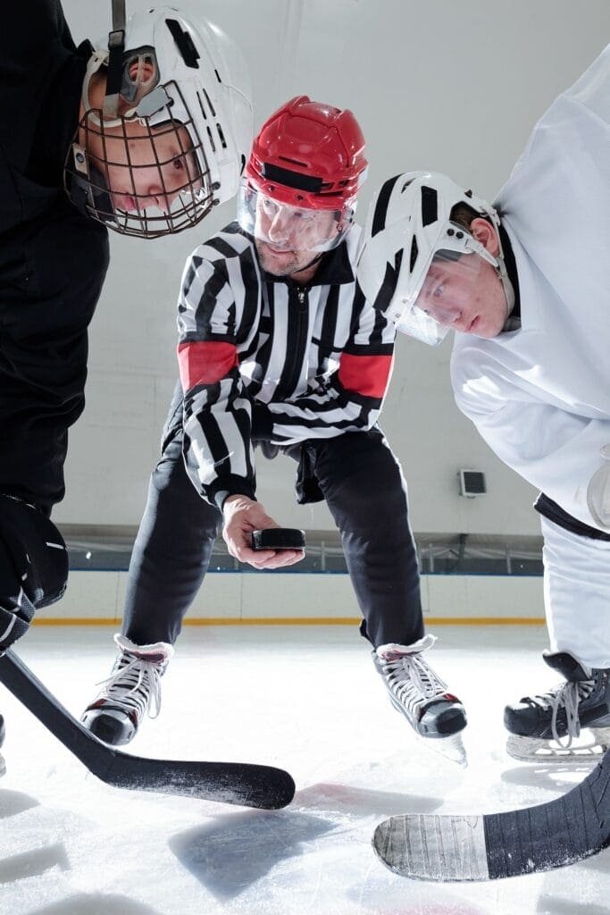hockey-referee-holding-puck-over-ice-rink-while-rivals-with-sticks-looking-at-it.jpg